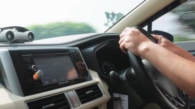 Bandung, Endonezya - 24 Kasım 2024; otoyolda yüksek hızda araba süren bir adamın eli