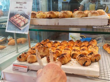 Bandung, Endonezya - 1 Ekim 2024; Bolen Lilit Pisang (Banana twist bolen) fırın vitrinlerindeki ahşap tepsilerde kutu başına 48 bin Rupiah veya 6 pc