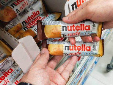 Bandung, Endonezya - 1 Aralık 2024; iki kişi Nutella B-hazır gofret tutuyor, fındıklı gofretler çikolata ile kaplanmış, marketlerin raflarında veya süpermarketlerin raflarında düzenlenmiş.