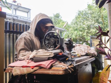 Bandung, Endonezya - 8 Aralık 2024; eski bir dikiş makinesi ile mobil terzi servisi, kıyafet, gömlek, pantolon, çanta, hatta yağmurluk tamir etmek için eve çağrılabilir