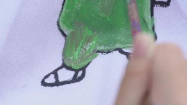 Suluboya ve fırça kullanarak küçük bir kızın elini boyamak, yaratıcılığı geliştirmek.