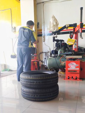 Bandung, Endonezya - 30 Mayıs 2023; Bir kayma ve dengeleme atölyesinde çalışan bir işçinin yeni bir çift araba lastiği takması