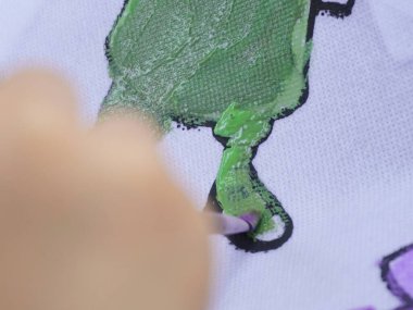 Bandung, Endonezya - 22 Aralık 2024; bir kız suluboya ve fırça kullanarak renkli çizgi film karakterlerine kendini kaptırdı, yaratıcılığı biledi