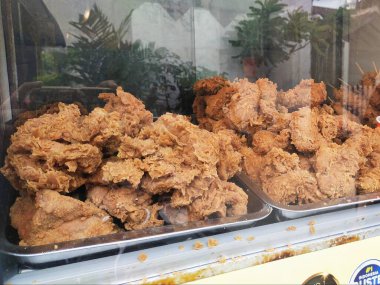 Fried chicken with a delicious crunch and authentic spices, sold in a glass display case clipart