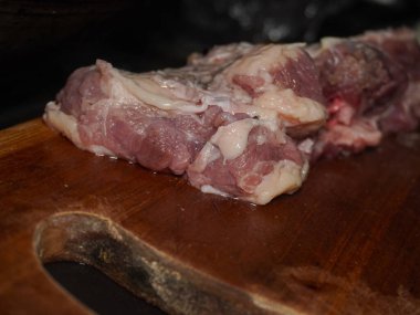 Doğrama tahtasının üzerinde çiğ et dilimleri. Et çiğ ve çok yağlı. Mutfakta yemek hazırlığı.