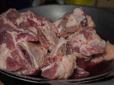 Çaydanlıkta bir yığın çiğ et var. Et çiğ ve çok yağlı. Mutfakta yemek hazırlığı.