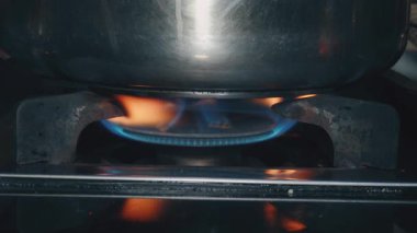 Gaz ocağındaki alevler. Fırında paslanmaz çelik tava, gaz sobasında pişirme.