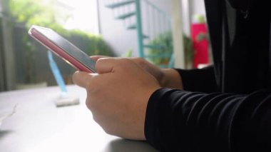 Masanın üzerinde cep telefonuyla yazı yazan bir kadının yakın çekimi.