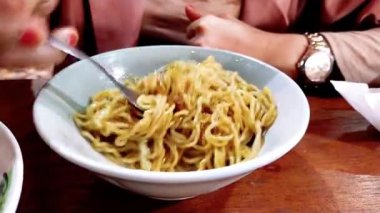 Mie Bakso yiyen bir kadın, ya da köfteli erişte çorbası, Endonezya 'nın en popüler mutfaklarından biri, sokak yemeklerinden, restoranlara kadar.