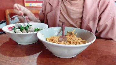 Bandung, Endonezya - 3 Nisan 2025; Mie Bakso yiyen bir kadın, veya köfteli erişte çorbası, Endonezya 'nın en popüler mutfaklarından biri, sokak yemeklerinden, restoranlara kadar
