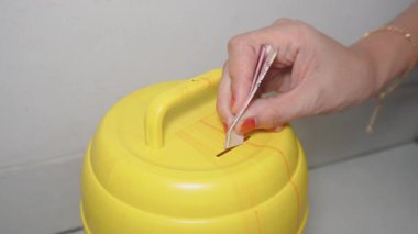 Bandung, Endonezya - 3 Nisan 2025; Hand Endonezya Rupiah 'ını geleneksel sarı bir plastik domuz kumbarasına koydu. Kapatın. Tasarruf kavramı