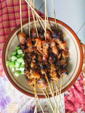 Masadaki tabakta salatalık turşusuyla servis edilen Endonezya sığır eti satayı. Sate sapi 