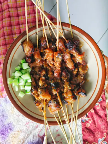 Masadaki tabakta salatalık turşusuyla servis edilen Endonezya sığır eti satayı. Sate sapi 