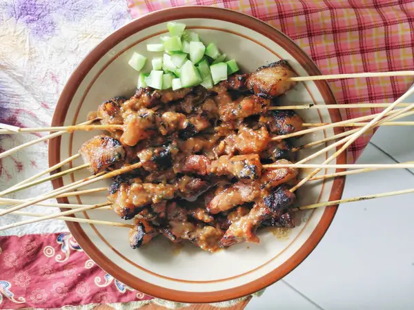 Masadaki tabakta salatalık turşusuyla servis edilen Endonezya sığır eti satayı. Sate sapi 