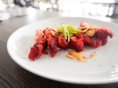 Lezzetli bir Çin yemeği, Char Siu Chicken veya kızarmış Char Siu Chicken veya Char Siew, kırmızı mayalı pirinçten yapılmış parlak kırmızı bir tavuk. Tahta bir masada beyaz bir tabakta servis edilir. Seçici odak