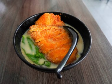 Zengin ve kremalı ramen eriştesi. Üstünde de tavuk katsu parçaları var.