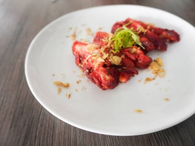 Lezzetli bir Çin yemeği, Char Siu Chicken veya kızarmış Char Siu Chicken veya Char Siew, kırmızı mayalı pirinçten yapılmış parlak kırmızı bir tavuk. Tahta bir masada beyaz bir tabakta servis edilir. Seçici odak