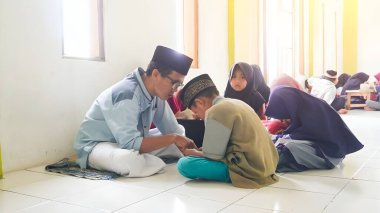 Bandung, Endonezya - 3 Ocak 2023; Çocuklar bir medresede bir öğretmenin rehberliğinde Kuran okumayı öğrenirler.