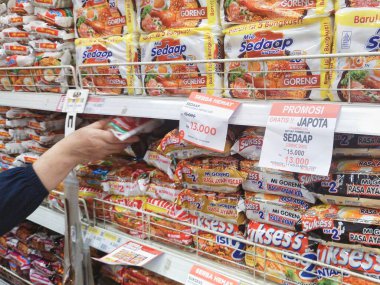 Bandung, Endonezya - 24 Nisan 2025; bir müşteri bir süpermarketin rafında çeşitli çeşitleri ve markalarla hazır erişte ürünleri satın alıyor.