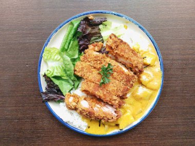 Kızarmış tavuk parçaları ve ahşap masada sebzeli Japon körili pilavı. Menü tasarımı, yemek blogu, restoran promosyonu ve daha fazlası için harika.