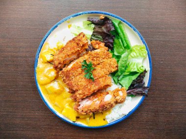 Kızarmış tavuk parçaları ve ahşap masada sebzeli Japon körili pilavı. Menü tasarımı, yemek blogu, restoran promosyonu ve daha fazlası için harika.