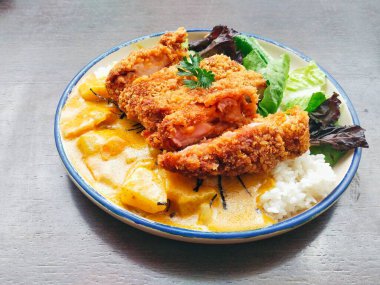 Kızarmış tavuk parçaları ve ahşap masada sebzeli Japon körili pilavı. Menü tasarımı, yemek blogu, restoran promosyonu ve daha fazlası için harika.