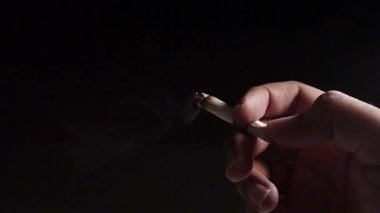 Siyah arka planda sigara içen adam elini kapat.