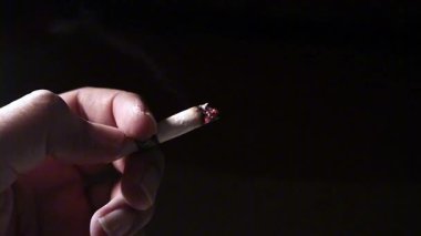 Siyah arka planda sigara içen adam elini kapat.