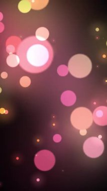 Bulanık pembe ve sarı ışıldayan parçacıklar. Bokeh renkli ışıklar koyu arkaplanda yüzüyor. 4k döngü dikey mobil canlandırması.
