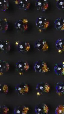 Siyah arka planda dağılım etkisi olan dönen cam toplar. Yeni yıl dekoratif desenleri. Kusursuz 4k dikey canlandırma.