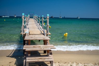 Saint-Tropez yakınlarındaki efsanevi Pampelonne plajındaki yatların misafirleri için ahşap iskele. Fransız Riviera, Fransa 'nın beyaz kumlu sahillerinde yaz tatili.