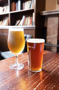 Pint glasses of cold fresh british ale and lager beer served in old vintage English pub