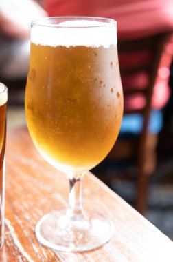 Pint glass of british light pilsner ot lager beer served in old vintage English pub, close up