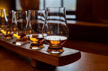 Flight of single malt scotch whisky in glasses served in bar in Edinburgh, UK, tasting of dram of whiskey