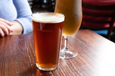 Pint glasses of cold fresh british ale and lager beer served in old vintage English pub