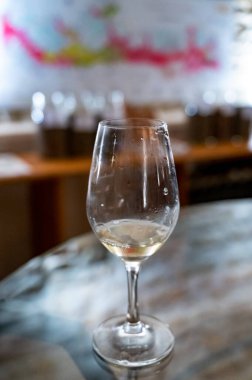 Wine tasting in underground cellars caves of French wine domain in Puligny-Motrachet village, Burgundy, France with map of Burgundy wine appelations and soils on background.