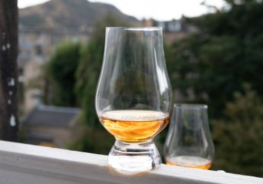 Glass of single malt scotch whisky served on old window sill in Scottisch house with view on old part of Edinburgh city, Scotland, UK, dram of blended whiskey