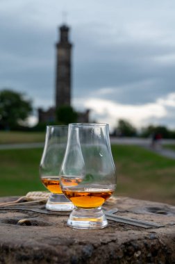 Tasting of single malt scotch whisky in glasses with panoramic view from Calton hill to new and old parts of Edinburgh city in rainy summer day, Scotland, UK