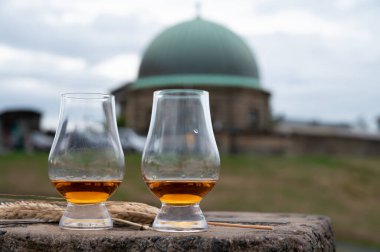 Tasting of single malt scotch whisky in glasses with panoramic view from Calton hill to new and old parts of Edinburgh city in rainy summer day, Scotland, UK
