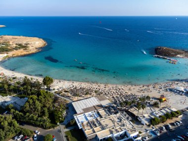 Kıbrıs Rum Kesimi 'nin Ayia Napa plajı yakınlarındaki Akdeniz' de tatil villaları ve tatil beldelerinde havadan panoramik manzara ve mavi kristal berrak su. Deniz tatili.