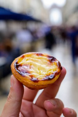Portekiz 'in geleneksel tatlı tatlısı Pastel de nata yumurtalı kremalı tart ve Lizbon, Portekiz' deki eski cadde manzaralı.