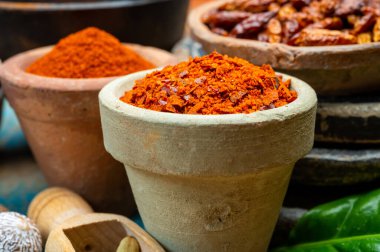 Renkli zemin baharatlı kırmızı biber, pimento ve curcuma ahşap masaya yakın kil çömlekler.