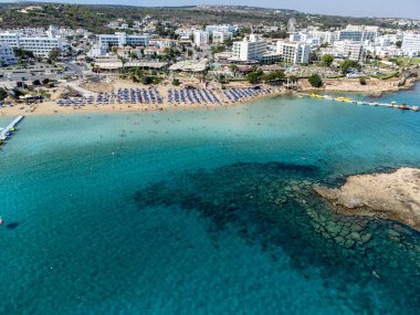 Villalar, tatil beldeleri ve Akdeniz 'deki kumlu incir ağacı plajı, Protaras, Kıbrıs Rum Kesimi yakınlarındaki mavi kristal berrak su üzerindeki hava panoramik manzarası