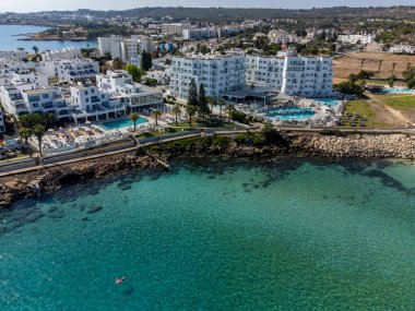 Villalar, tatil beldeleri ve Akdeniz 'deki kumlu incir ağacı plajı, Protaras, Kıbrıs Rum Kesimi yakınlarındaki mavi kristal berrak su üzerindeki hava panoramik manzarası