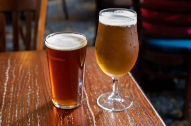 Pint glasses of cold fresh british ale and lager beer served in old vintage English pub