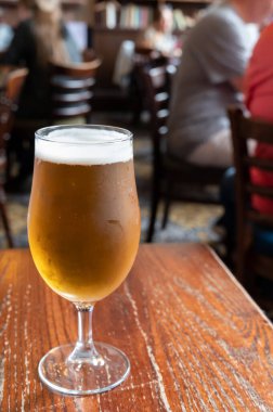Pint glass of british light pilsner ot lager beer served in old vintage English pub, close up