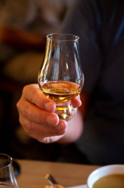 Tasting of single malt scotch whisky in scottish bar in Edinburgh, UK, hand with glass of whisky