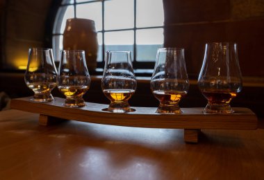 Flight of single malt scotch whisky in glasses served in bar in Edinburgh, UK, tasting of dram of whiskey