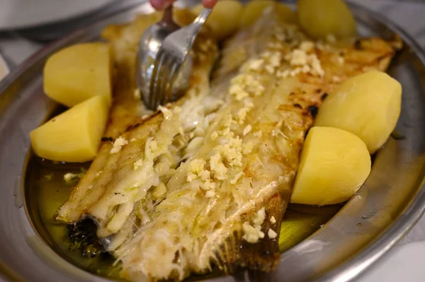 ポルトガルの魚料理店でジャガイモを添えて提供される白コードフィッシュバカラのグリルフィレ — ストック写真