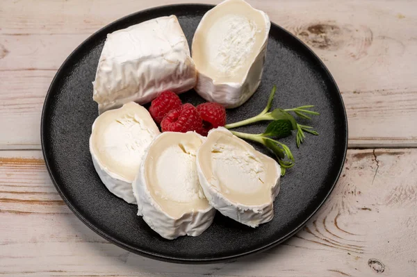 フランスの有機成熟した白ヤギチーズと白いカビが閉じられ 新鮮なラズベリーとグリーンが添えられています — ストック写真
